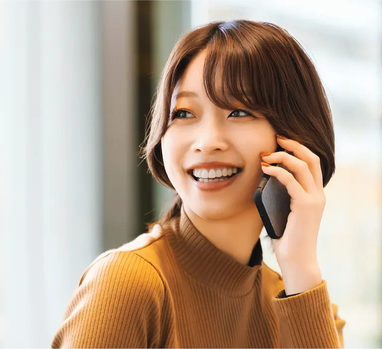 女性が笑顔で電話をしている